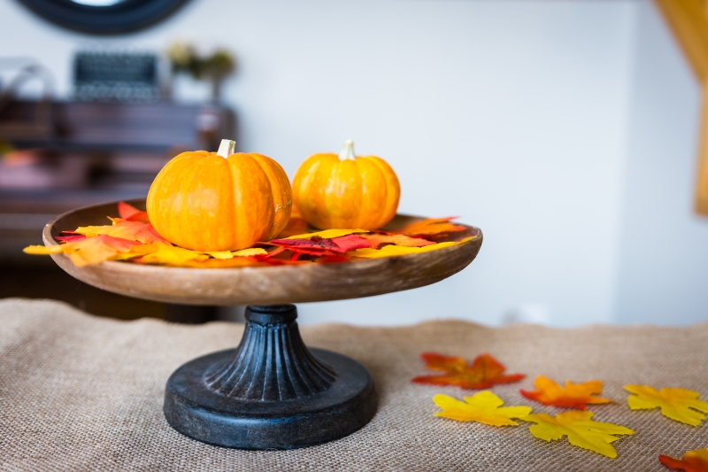 Fall-themed dining room centerpiece with pumpkins, leaves and burlap runner - LightsOnline Blog